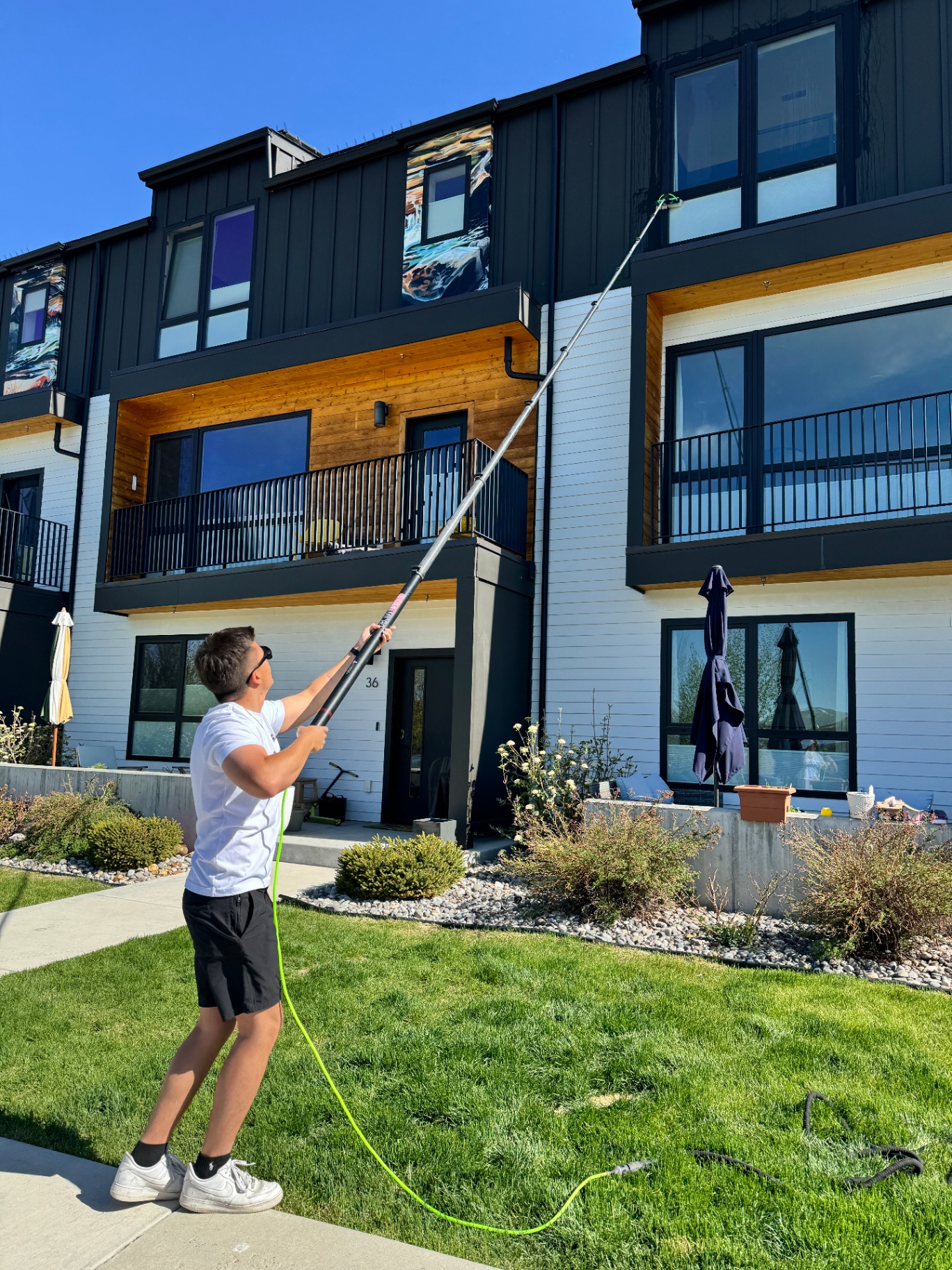 Doral Window Cleaning Pros technician using a water-fed pole to clean second-story windows on a modern home