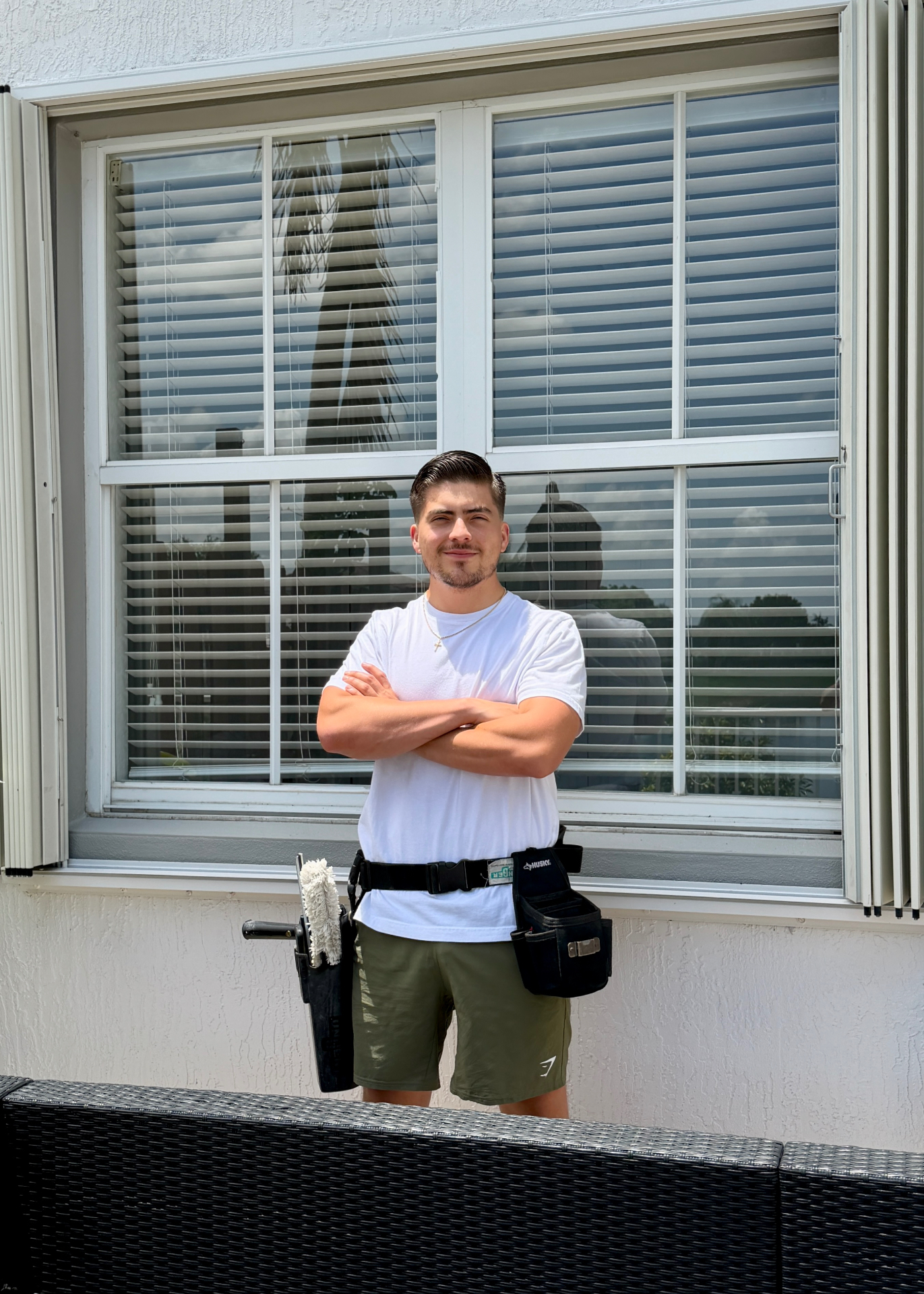 Glassy technician using a water-fed pole to clean second-story windows on a modern home